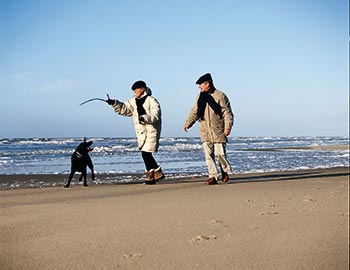 Ektepar med hund går tur på stranden